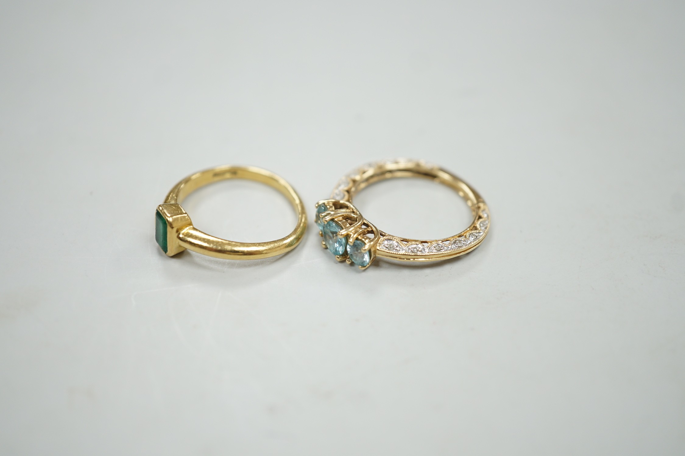 A modern 18ct gold and single stone emerald set ring, size M, gross weight 4 grams and a modern 14k and three stone blue zircon dress ring, with diamond chip set shank, size P, gross weight 3.4 grams.